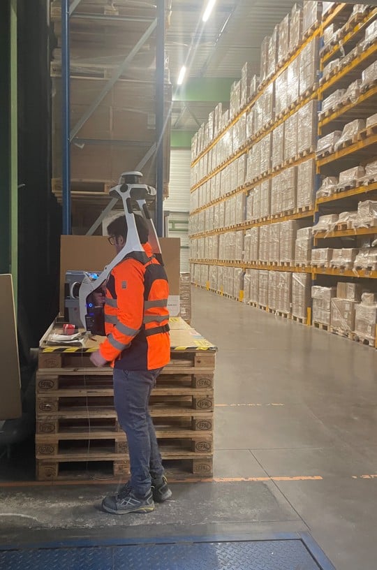 un geometre porte sur son dos un navvis vlx pour mesurer un entrepot logistique